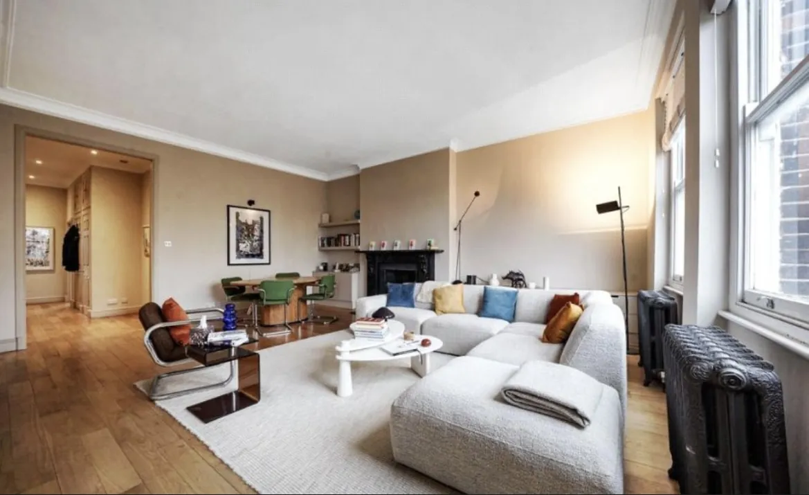 Open living room with wooden floors, a corner sofa and a dining table